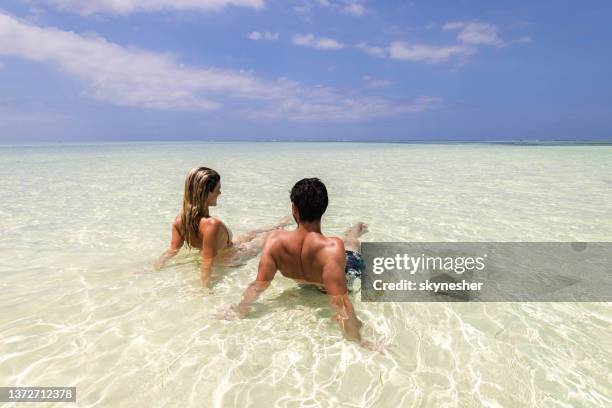 vista posteriore di una coppia che si rilassa in mare poco profondo. - zanzibar foto e immagini stock