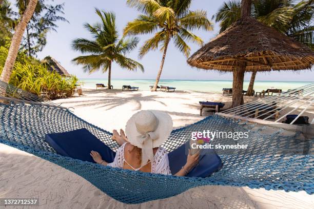 vista sul retro di una donna rilassata con frullato in amaca sulla spiaggia. - zanzibar foto e immagini stock