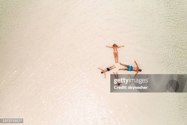 above view of a family relaxing in shallow water at sea. - mother and child in water at beach stock pictures, royalty-free photos & images