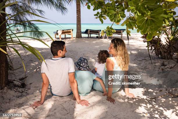 back view of happy family relaxing in a shade on the beach. - family greenery bildbanksfoton och bilder