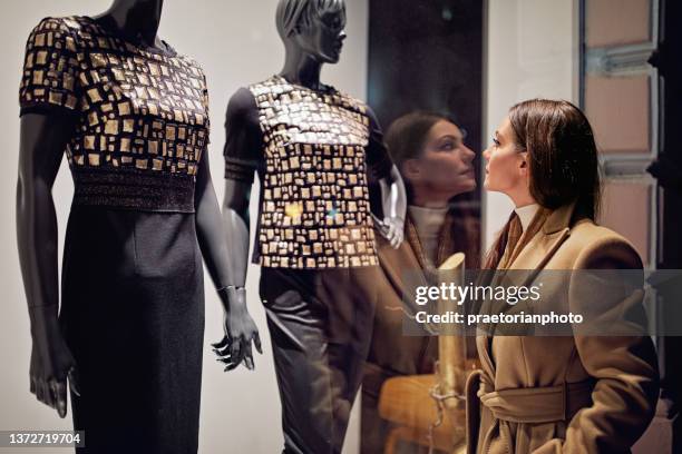 young woman is looking store window on the street - mannequin stockfoto's en -beelden