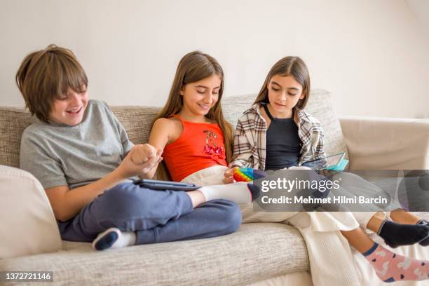 beautiful girls and boy using digital tablet and enjoying antistress rainbow pop it fidget - ass stockfoto's en -beelden
