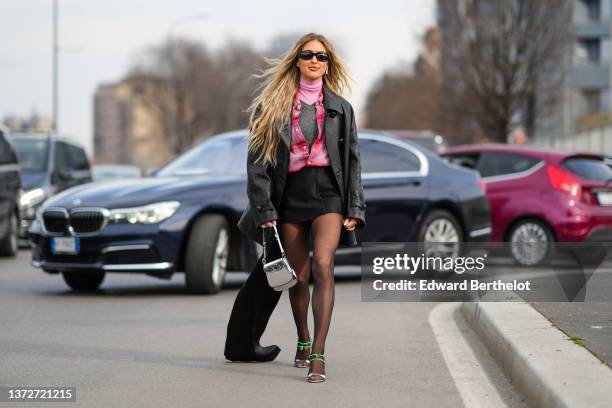 Emili Sindlev wears black sunglasses, a pale pink turtleneck t-shirt, a gray V-neck wool pullover, a pink / orange / red checkered print pattern...