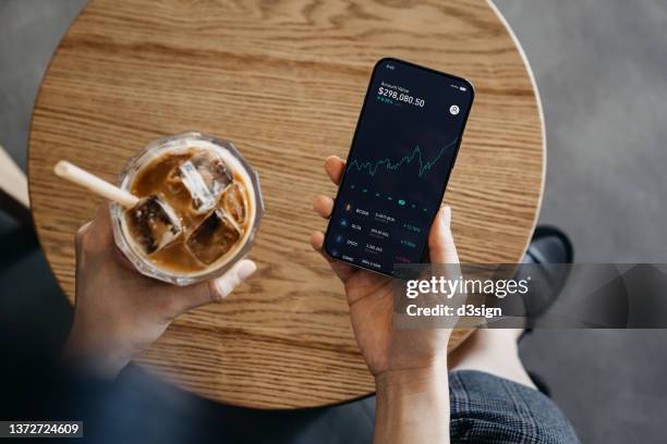 overhead view of young asian woman using nft investment wallet on smartphone while having coffee in cafe, working with blockchain technologies, investing or trading nft (non-fungible token) on cryptocurrency, digital asset, art work and digital ledger - bitcoin phone stock pictures, royalty-free photos & images