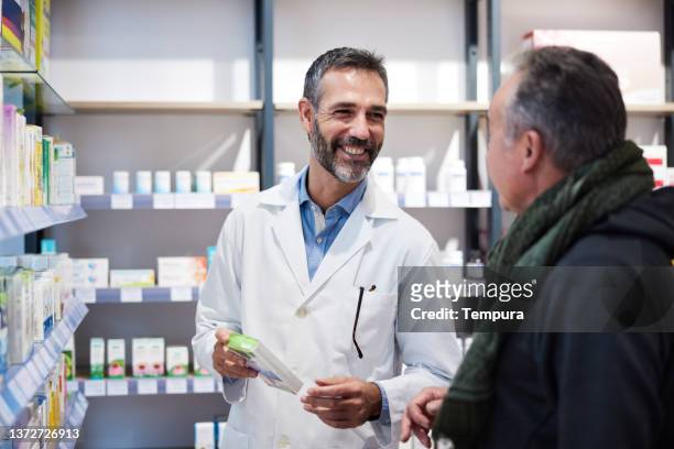 un farmacéutico está atendiendo a un hombre mayor. - medicamentos fotografías e imágenes de stock