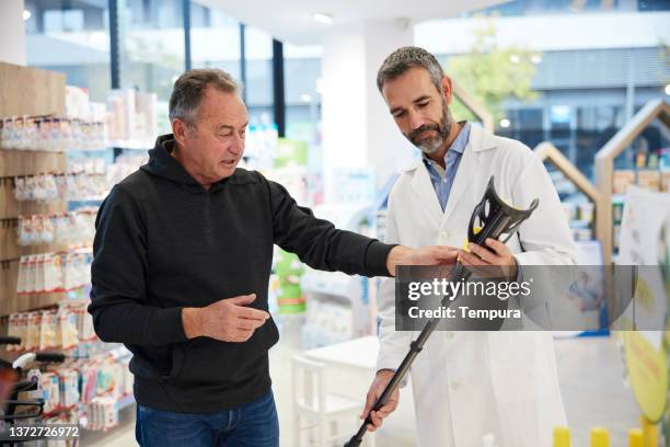 ein drogeriekunde und ein apotheker unterhalten sich im laden. - krücken stock-fotos und bilder