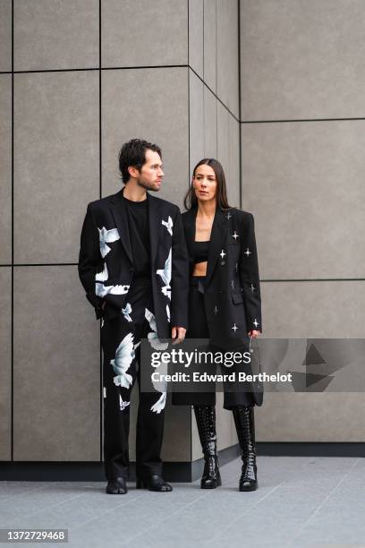 Jean-Sebastien Rocques wears a black t-shirt, a black with large white bird print pattern blazer jacket, matching black with large white bird print...