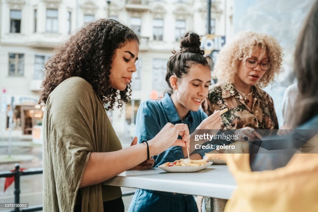 Vier Teenager-Mädchen essen Currywurst mit Pommes frites in Berlin