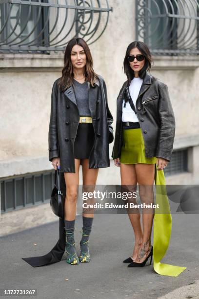 Gilda Ambrosio wears black sunglasses from Ray Ban, a white t-shirt, a black shiny leather crossbody bag from Prada, a black faded leather oversized...