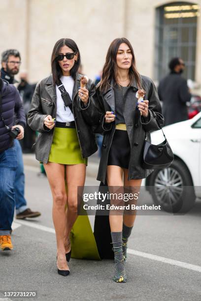 Gilda Ambrosio wears black sunglasses from Ray Ban, a white t-shirt, a black shiny leather crossbody bag from Prada, a black faded leather oversized...