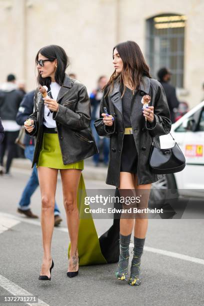 Gilda Ambrosio wears black sunglasses from Ray Ban, a white t-shirt, a black shiny leather crossbody bag from Prada, a black faded leather oversized...