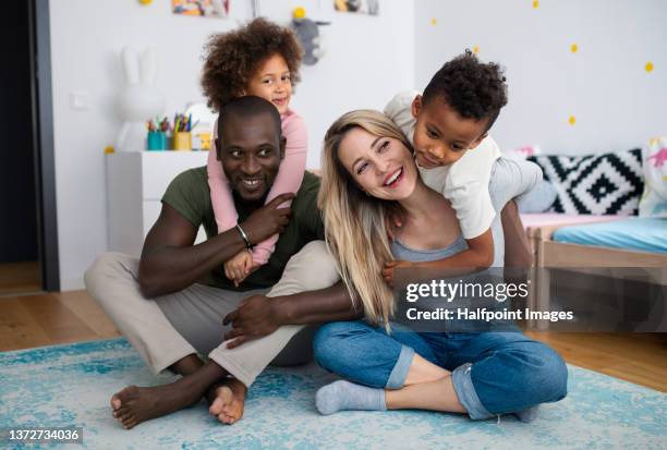 two little multiracial kids with mother and father playing with toy planes at home. - diverse family stock-fotos und bilder