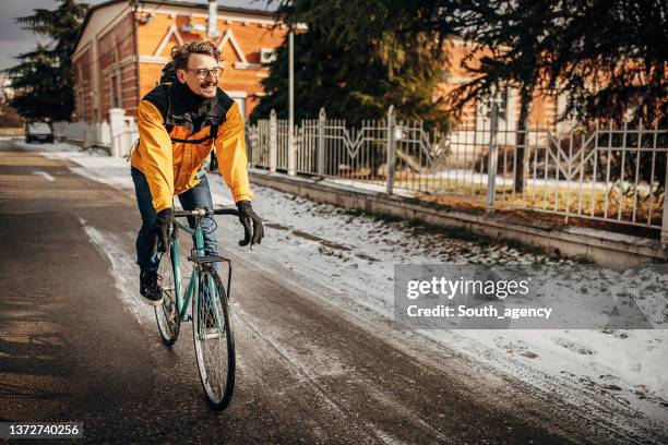 man riding bicycle on the street - winter cycling stock pictures, royalty-free photos & images