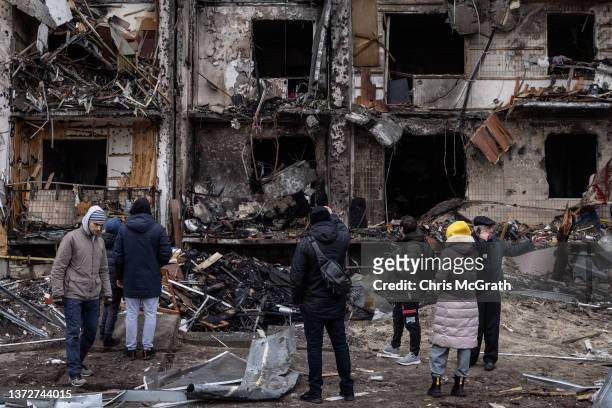 People look at the exterior of a damaged residential block hit by an early morning missile strike on February 25, 2022 in Kyiv, Ukraine. Yesterday,...
