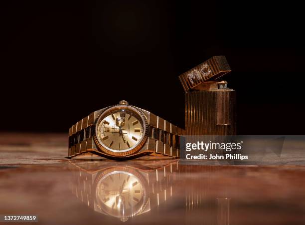 Sir Michael Caine's Rolex, an 18K gold quartz calendar bracelet watch, and a diamond-set ‘Collages’ lighter are seen on display during a photocall...