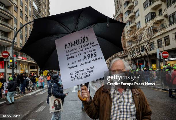 Demonstrator with umbrella, with a banner that reads 'Attention gift 35,000 kgs of tangerines, The field dies the farmer is risked', in a rally for...