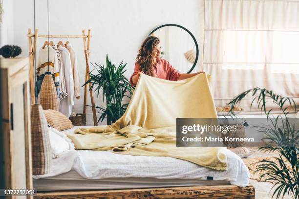 woman doing her morning routine, arranging pillows and making up bed at home. - white blanket stockfoto's en -beelden