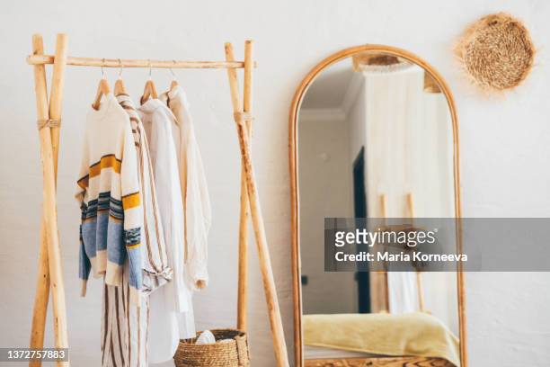 clothes hanging on a hangers near a mirror at  home. - wardrobe stock pictures, royalty-free photos & images