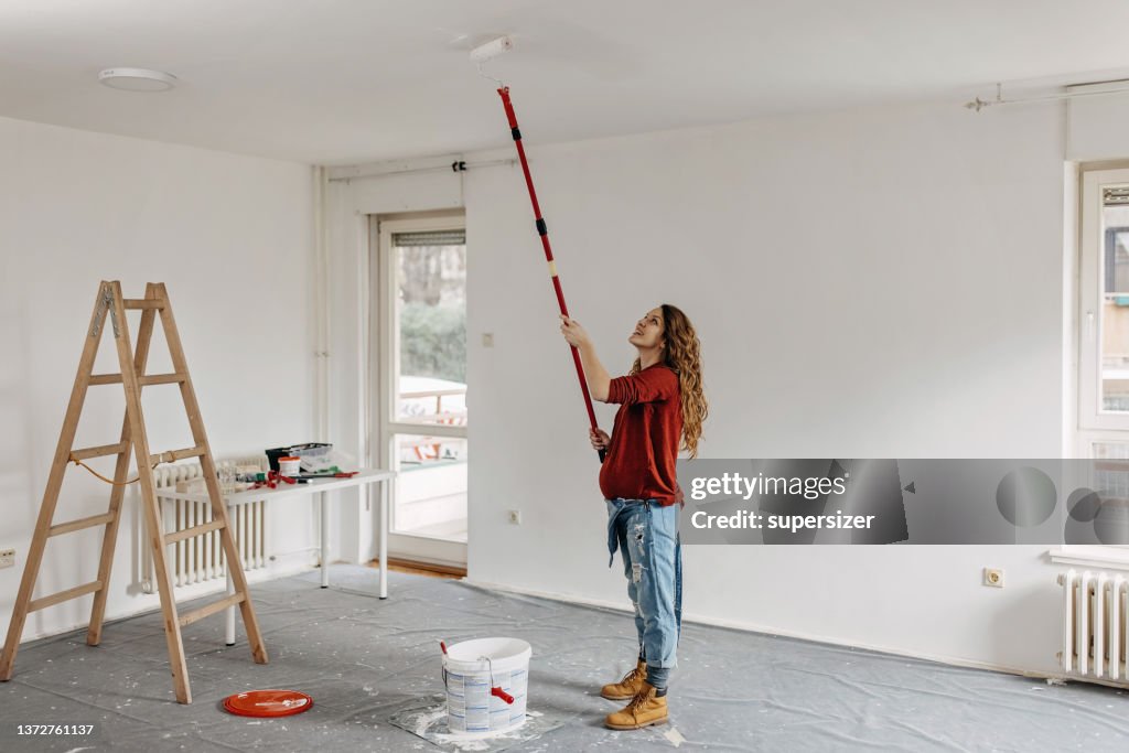 Young pregnant woman painting nursery room