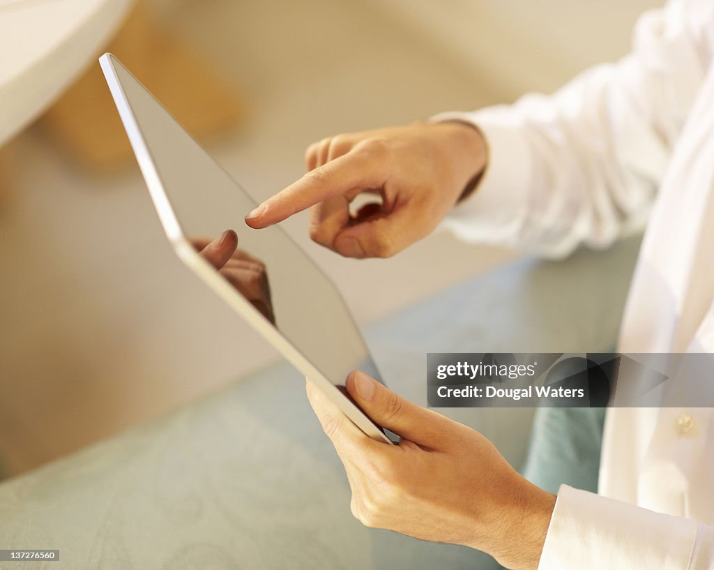 Person using digital tablet at home.