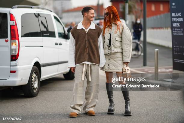 Guest wears a white oversized shirt, a dark brown ribbed wool buttoned sleeveless cardigan, beige large pants, brown suede ankle boots from UGG, a...