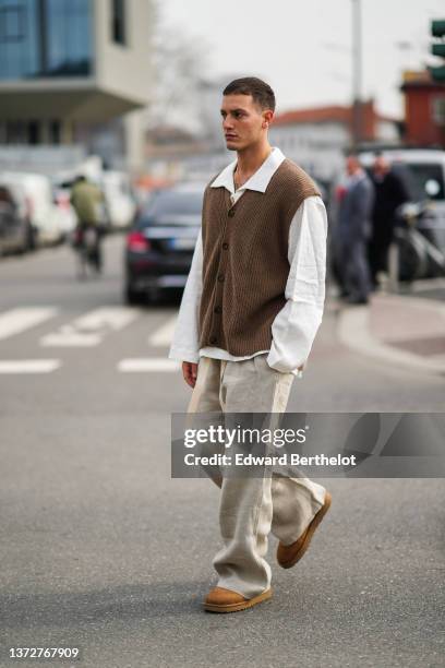 Guest wears a white oversized shirt, a dark brown ribbed wool buttoned sleeveless cardigan, beige large pants, brown suede ankle boots from UGG,...