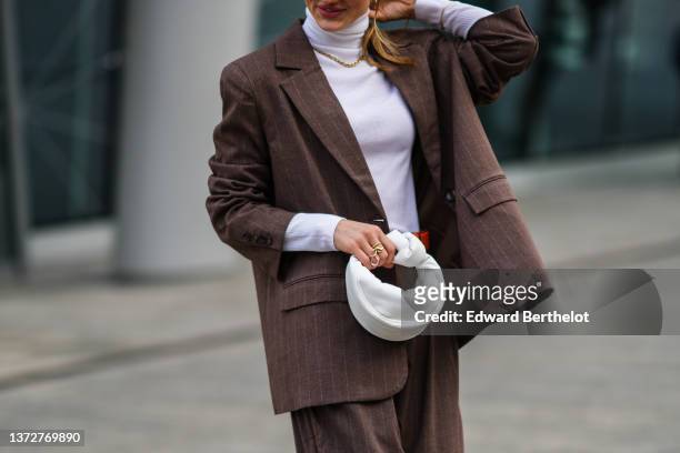 Guest wears a white ribbed wool turtleneck pullover, a dark brown and small white striped print pattern oversized blazer jacket, matching dark brown...