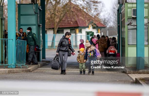 People walk with their belongings at the Tiszabecs-Tiszaujlak border crossing as they flee Ukraine on February 25, 2022 in Tiszabecs, Hungary. Long...