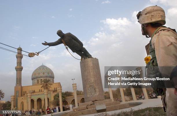 Marine of 3rd Batallion 4th Marine watch the statue of Sadam Hussein is taken down by Iraqi prople with help by Marine's M88 Vehicle at downtown...