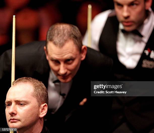 Graeme Dott , referee Brendan Moore and Allister Carter line up a shot during day four of The Masters at Alexandra Palace on January 18, 2012 in...