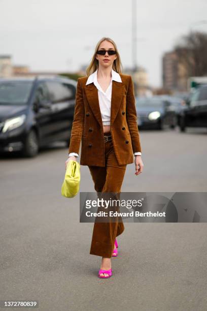 Guest wears sunglasses, a white cropped shirt, a brown ribbed velvet blazer jacket, matching brown ribbed velvet flared pants, a gold chain and logo...