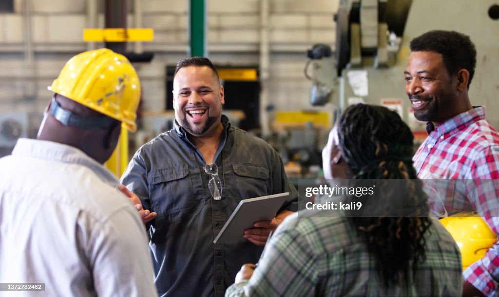 Multiracial group working in factory having meeting