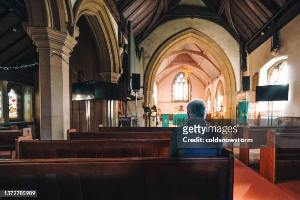 älterer mann, der in einer alten anglikanischen kirche betet - praying church stock-fotos und bilder