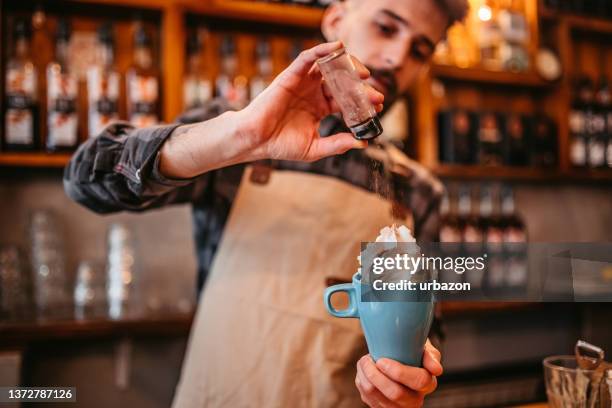 barista is spreading cinnamon on a coffee with whipped cream - whipped cream bildbanksfoton och bilder