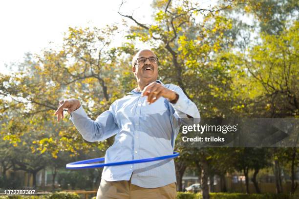 senior man exercising with hula hoop at park - hooping stock pictures, royalty-free photos & images