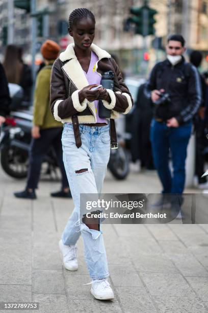 Model wears a pale purple with yellow print pattern V-neck wool pullover, a dark brown leather with large white sheep collar and borders zipper...