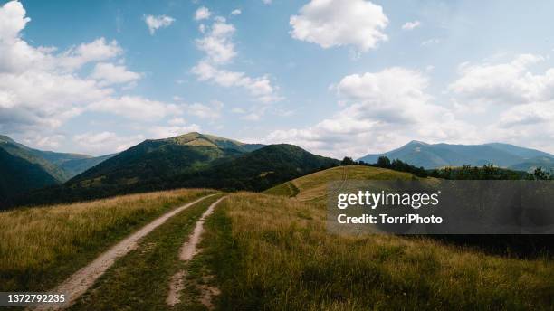 dirty road in mountain valley - distant hills stock pictures, royalty-free photos & images