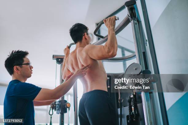 atleta asiatico cinese chin up allenamento trazione con il bicipite durante l'esercizio di routine in palestra barra orizzontale - issare foto e immagini stock