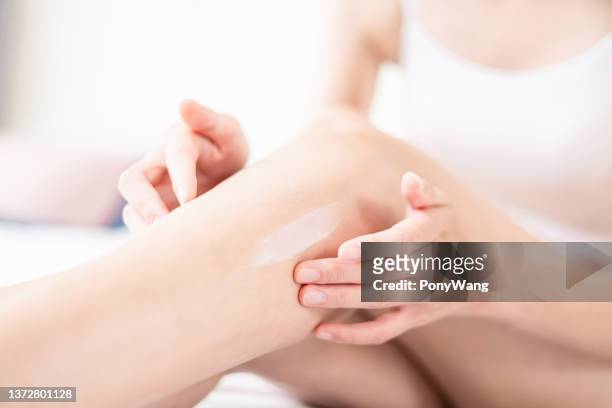 body care woman apply lotion - scheenbeen stockfoto's en -beelden