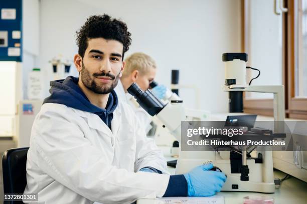 portrait of medical student using microscope - optical character recognition stock pictures, royalty-free photos & images