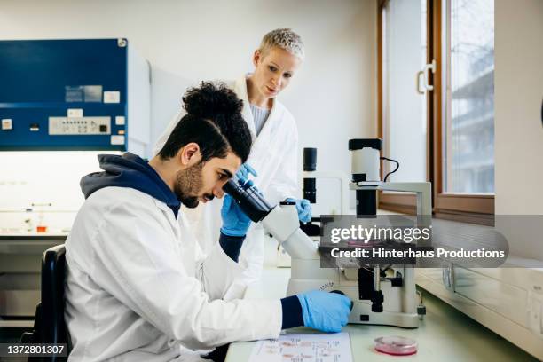 medical student using microscope in laboratory - laborkittel stock-fotos und bilder