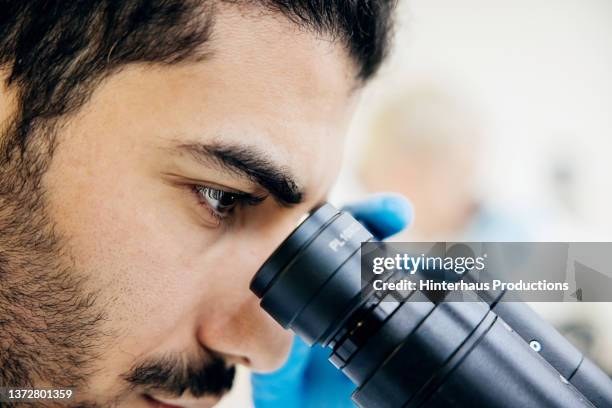close up of medical student looking through microscope - mikroskop stock-fotos und bilder