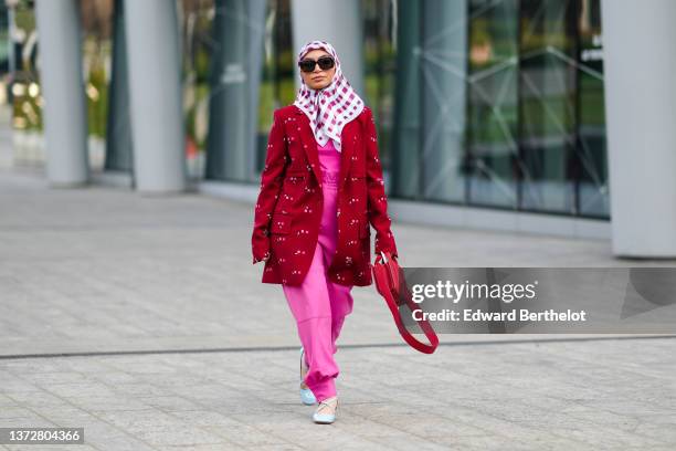 Guest wears black sunglasses, a red and white checkered print pattern scarf in the head, a neon pink t-shirt, matching neon pink high waist pants, a...