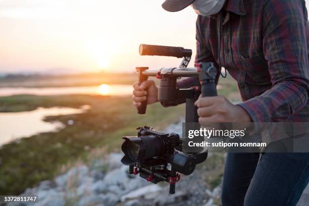 content creator using stabilizer gimbal camera take video footage on the location outdoor - filmregisseur stockfoto's en -beelden