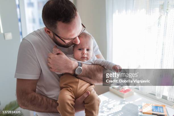 hombre sosteniendo al bebé con el ceño fruncido y oliendo su cabello de bebé - canción infantil fotografías e imágenes de stock
