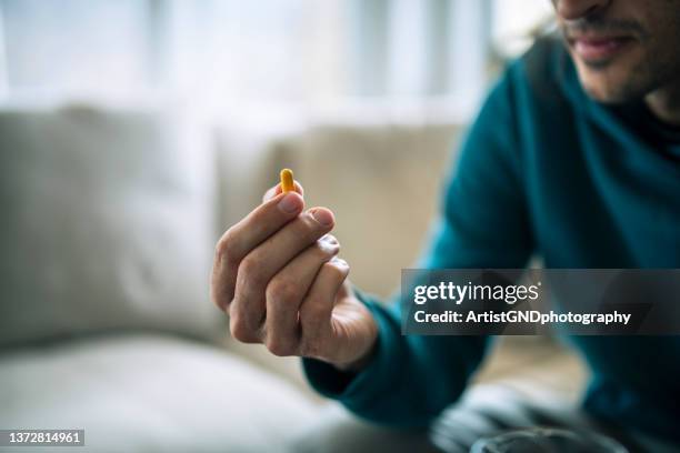 homme tenant une pilule jaune. - prendre des cachets photos et images de collection