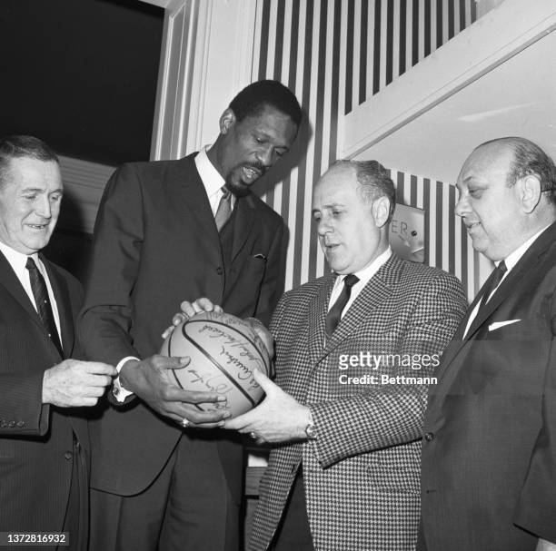 Bill Russell was named as new coach of the Boston Celtics and became the first black coach in the NBA. Russell and Auback look over an autographed...