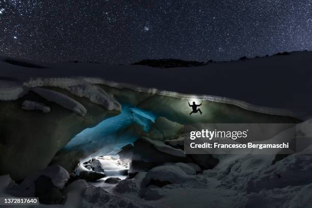 ice climber climbed a ice glacier cave with head lamp. above the night sky. morteratsch glacier, canton of graubunden(grisons), switzerland, europe. - ice pick ストックフォトと画像