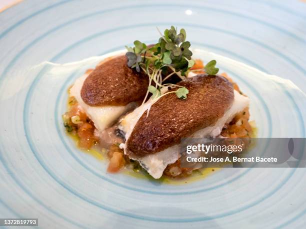 dish of cod confit with tomato and cauliflower with black garlic. - goldbrasse stock-fotos und bilder