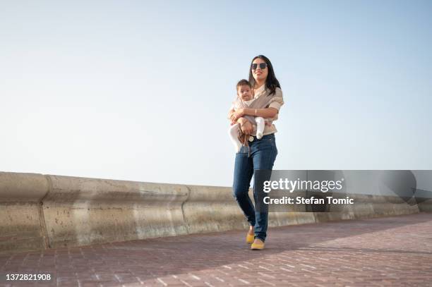 mãe carregando bebê bebê em um bebê portador e passando um tempo ao ar livre em um dia ensolarado - chinese mothers day - fotografias e filmes do acervo